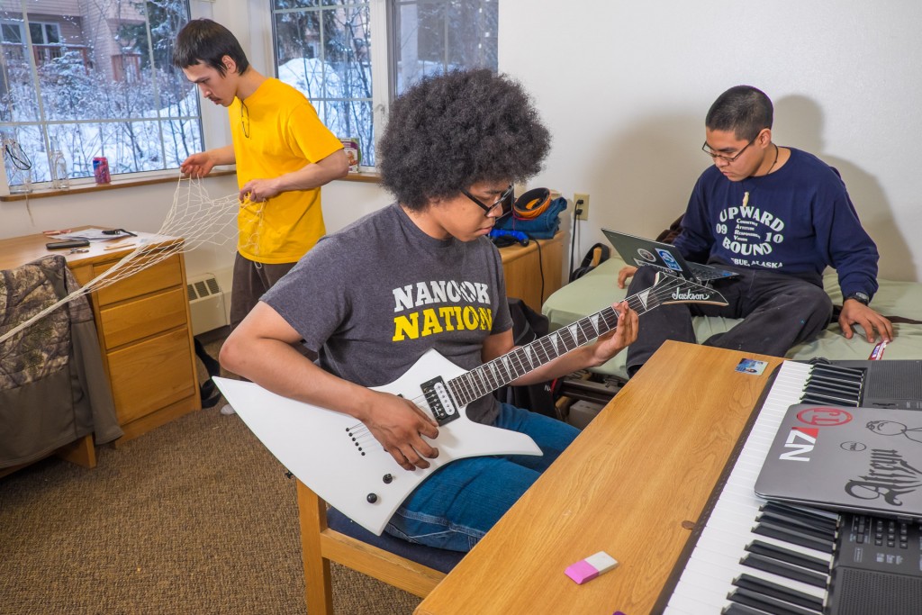 Terrell Jones, a computer science major from Deering, practices guitar in his room in the Eileen Panigeo MacLean House while fellow resident Christian Paul works on his net-mending skills and Ivik Henry surfs the Internet.