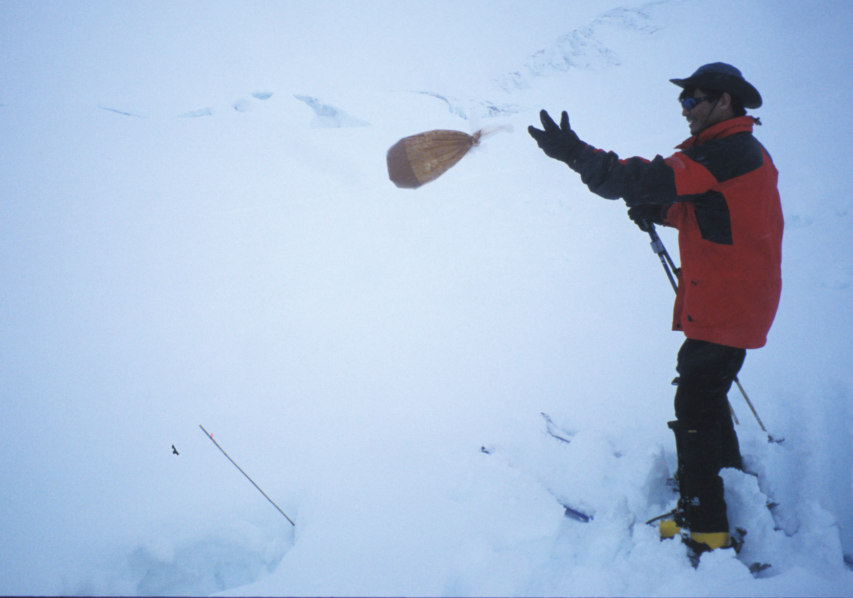Photo by Ned Rozell. Tohru Saito of UAF’s International Arctic Research Center disposes of a bag of human waste into a crevasse on Kahiltna Glacier during a 2003 climb up Denali’s West Buttress route.