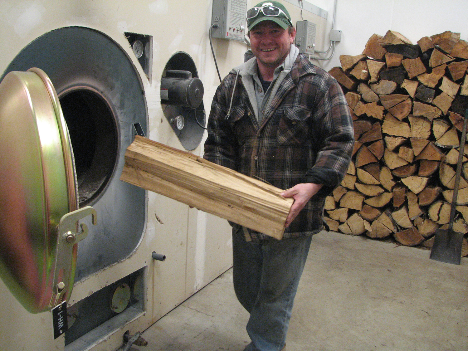 Karen Petersen photo. Jon Fitzpatrick loads firewood in the boiler at the Coffman Cove school. The school is part of an Oct. 8 preconference tour of Prince of Wales Island biomass projects.