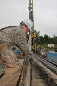 Photo courtesy of ACEP. A USGS crew member guides a drilling rod into place during the 2012 exploration program.