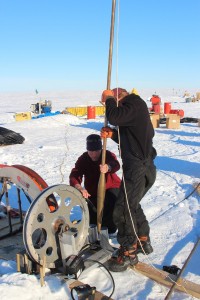Photo by Dale Pomraning. Bill Shaw and Martin Truffer lower a reamer into the borehole to melt it to a bigger diameter. 
