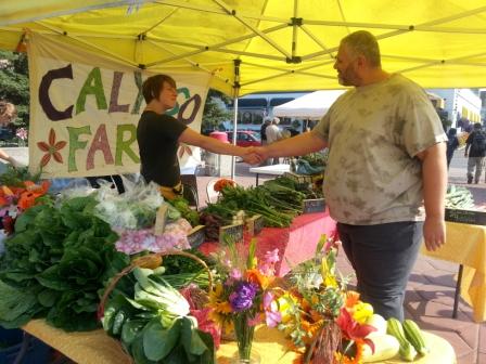 Photo courtesy of Calypso Farm and Ecology Center.. A customer is welcomed at the Downtown Farmers Market.