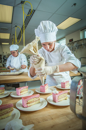 Stephanie Valentik applies whipped cream to a batch of raspberry tarts being served during lunch at CTC's culinary arts kitchen in the Hutchison Center. Photo by Todd Paris.