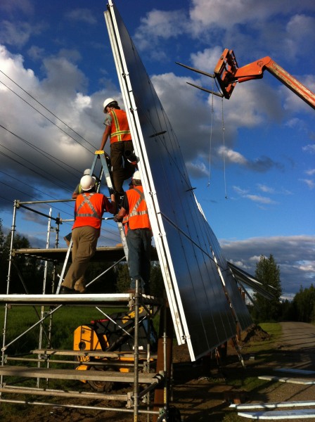 Workers install solar power panels.