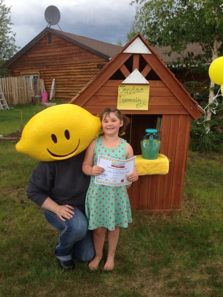 A young entrepreneur poses with the Lemonade Day mascot at her North Pole lemonade stand last June.