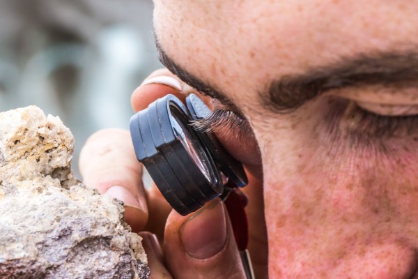 UAF photo by Todd Paris.. Getting up close and personal with rocks: A researcher looks at the crystals that have formed in a rock found in the Wrangell Mountains.