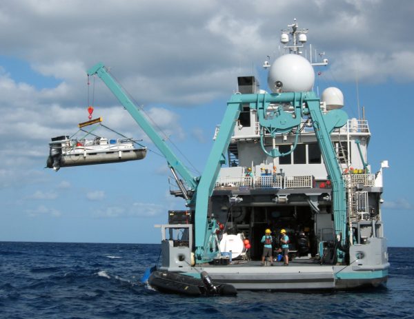 Photo courtesy of Chris Maio.  A pontoon boat from the Woods Hole Oceanographic Institution is offloaded by a research vessel while studying a blue hole in the Caribbean.