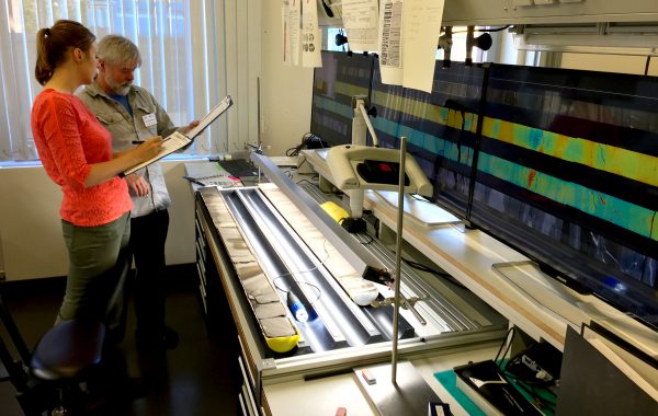 Photo by Kevin Kurtz.  Elise Chenot, of the Université de Bourgogne-Franche Comté, left, and Michael Whalen, of the UAF Geophysical Institute, examine a rock core from the Chicxulub crater in a lab in Bremen, Germany.