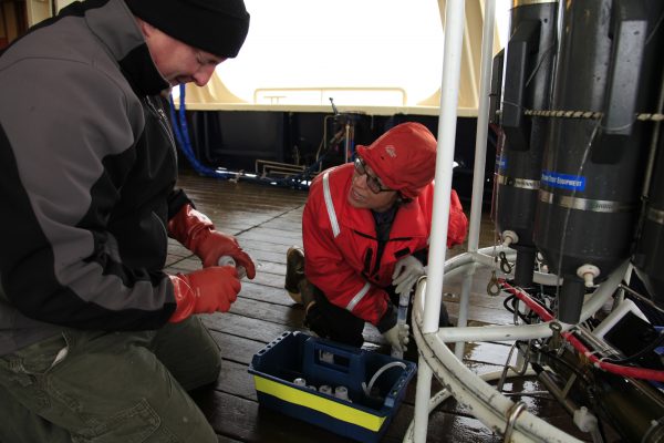 Photo by Jennifer Questel.  UAF's Pat Rivera, with Nick Delich from the NOAA Pacific Marine Environmental Laboratory, samples from an oceanography instrument during a 2014 cruise in the Gulf of Alaska.