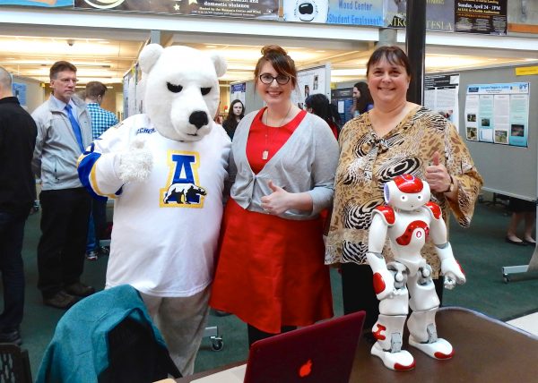 Elizabeth Smith, center, won the School of Education Dean's Choice Award and third place overall in the annual Research Day awards sponsored by the Office of Undergraduate Research and Scholarly Activity. Smith stands between the Nanook mascot bear and her mentor, Assistant Professor of Special Education Joanne Healy. School of Education Dean Steve Atwater is in the background at left.