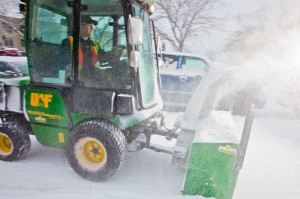 Paul Dick, an equipment operator for Facilities Services, blows snow from a campus sidewalk after a November dusting. 