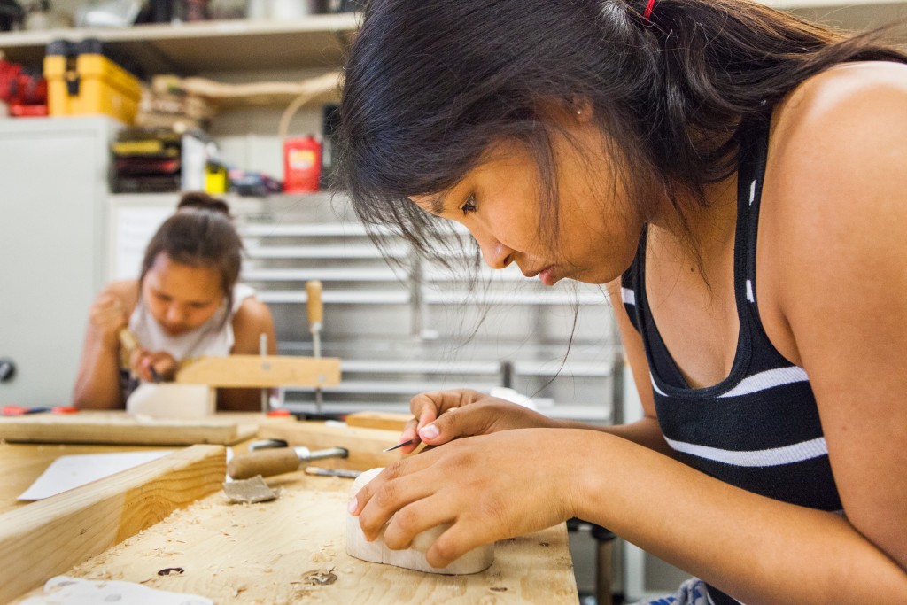Fourteen-year-old Outward Bound student Makayla Kameroff carves a mask at the Native Art Studio on campus Thursday, June 25, 2015.