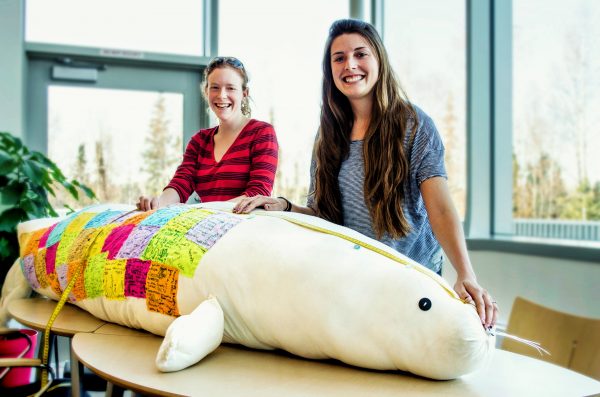 Photo by Rachel Lee. Amy Kirkham, left, and Roxanne Beltran created a life-size, stuffed seal named Patches that they have brought to visit 4,000 K–12 students in Alaska. Each student signed one of the fabric patches.
